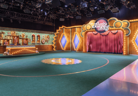 A television set on a large soundstage. Lights hang from the ceiling.