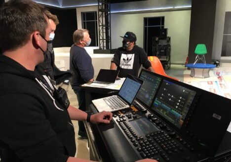 Lighting director stands behind a lighting board in a sound stage.